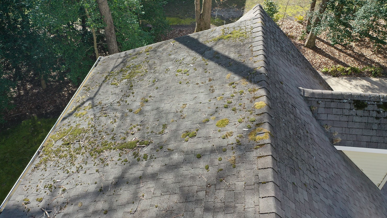 Close-up of a continuous ridge vent installed along the full length of a residential roof peak, photographed against a clear sky. 