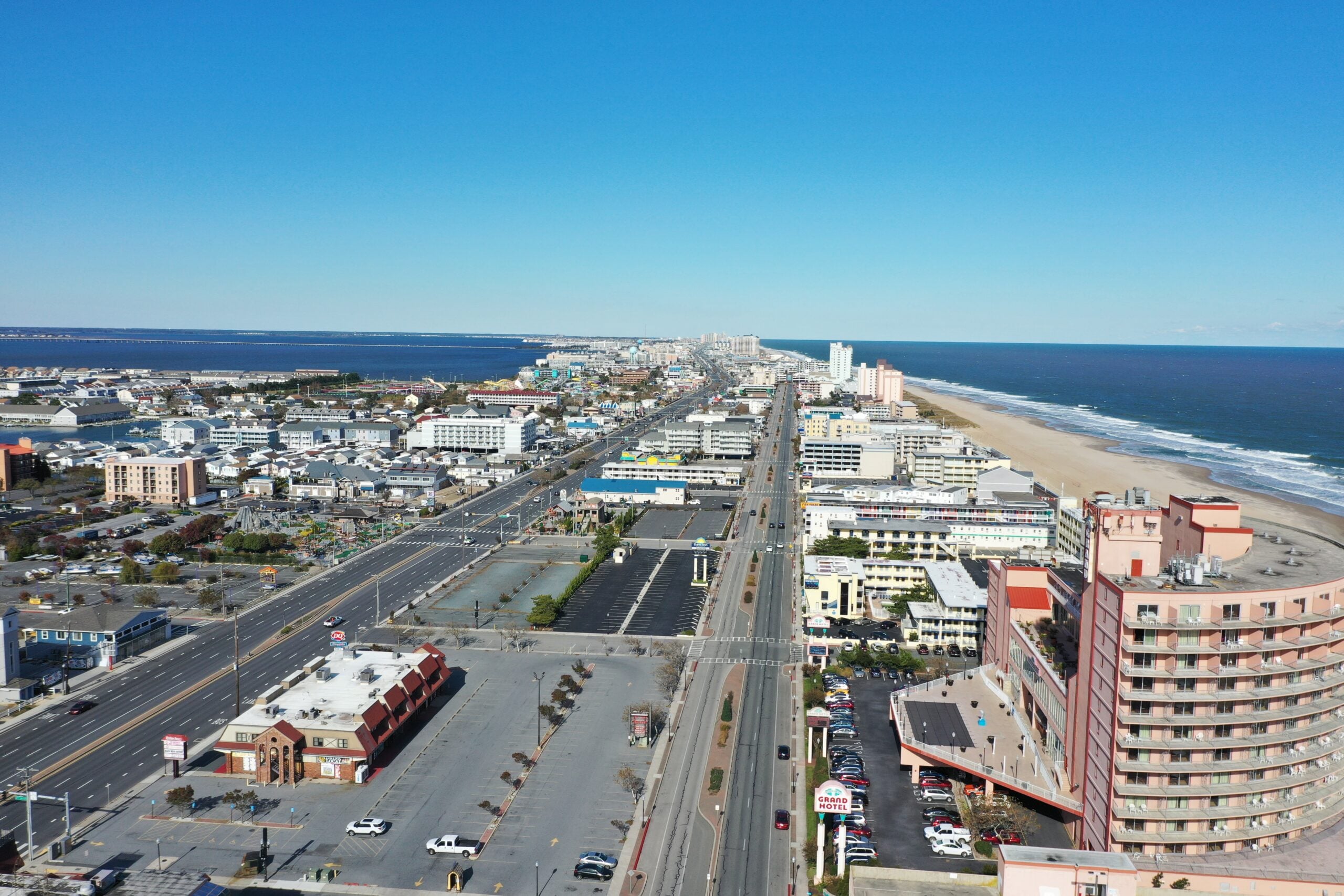 Aerial photo of an Ocean City, MD residential neighborhood after a summer storm. Overcast sky, scattered shingle damage visible on rooftops, natural daylight, real job photo style.