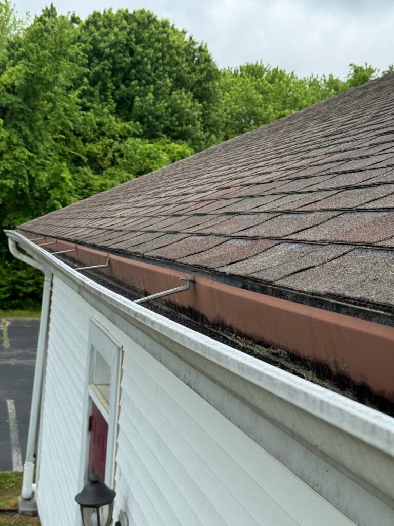 Used - white gutters on a house. The shingles seem to be reddish.