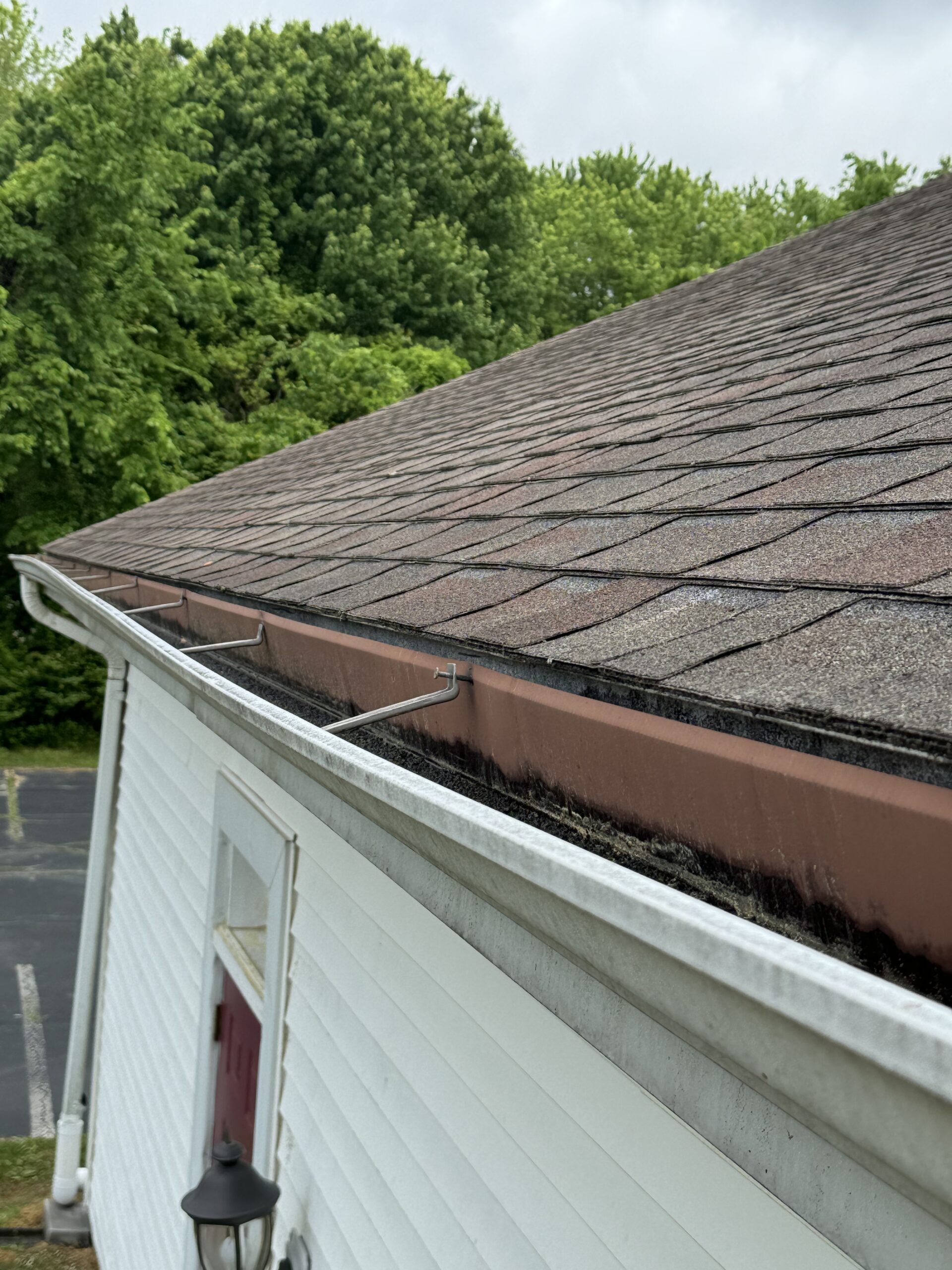 Used - white gutters on a house. The shingles seem to be reddish.