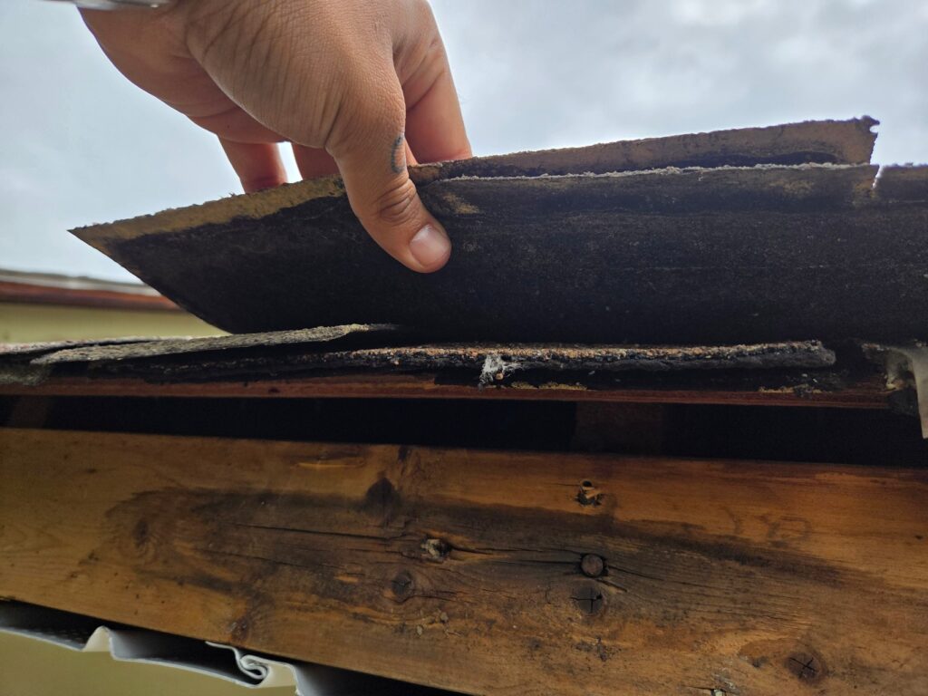 Used - Guillermo Molina Matus doing a roof inspection on a house with multiple layers of shingles. G and Bros Roofing