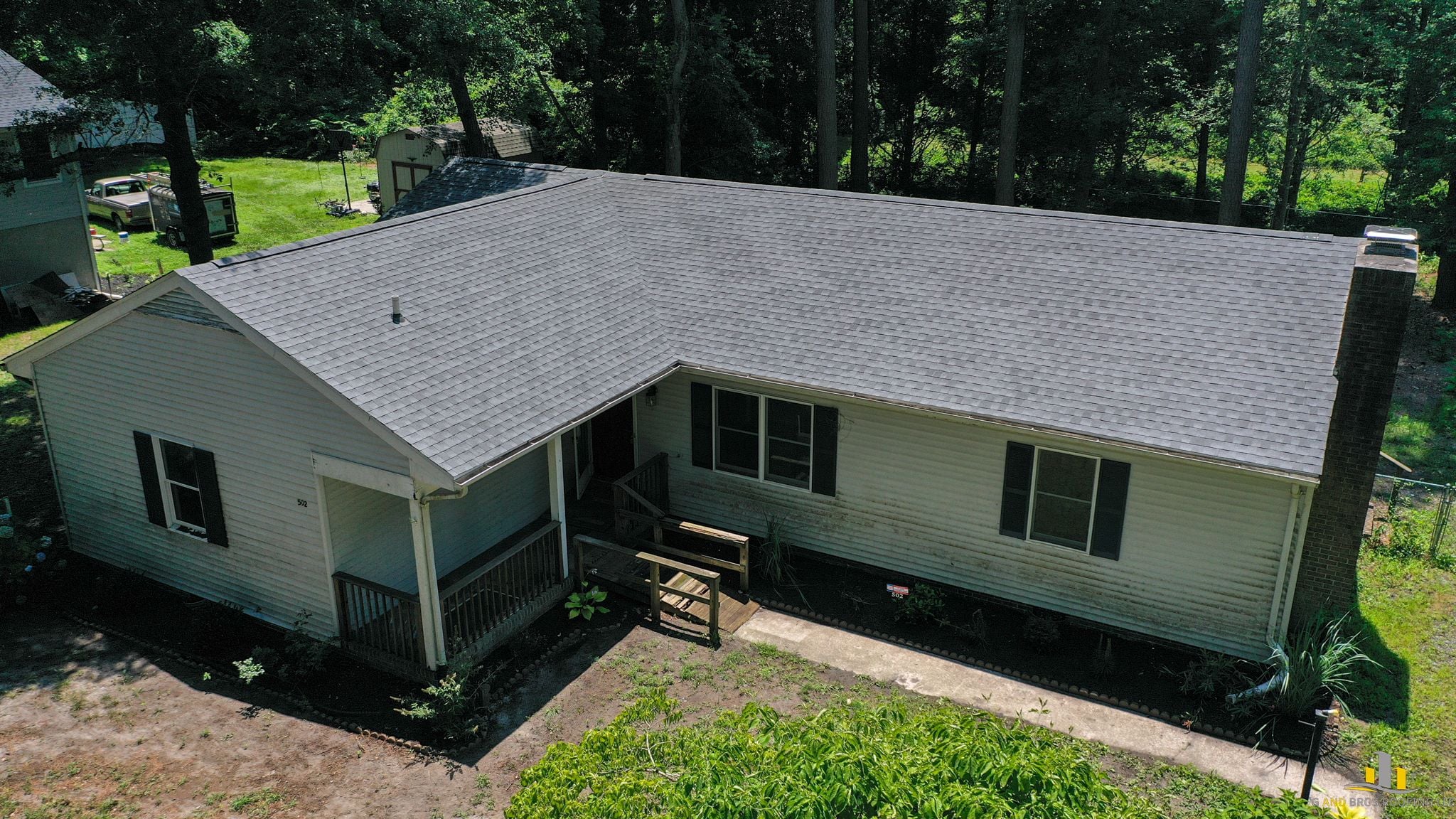 Freshly installed architectural asphalt shingles on an Eastern Shore residential home, wide shot showing clean ridge lines, uniform color, and new drip edge. Clear blue sky, real G and Bros completed job photo strongly preferred.