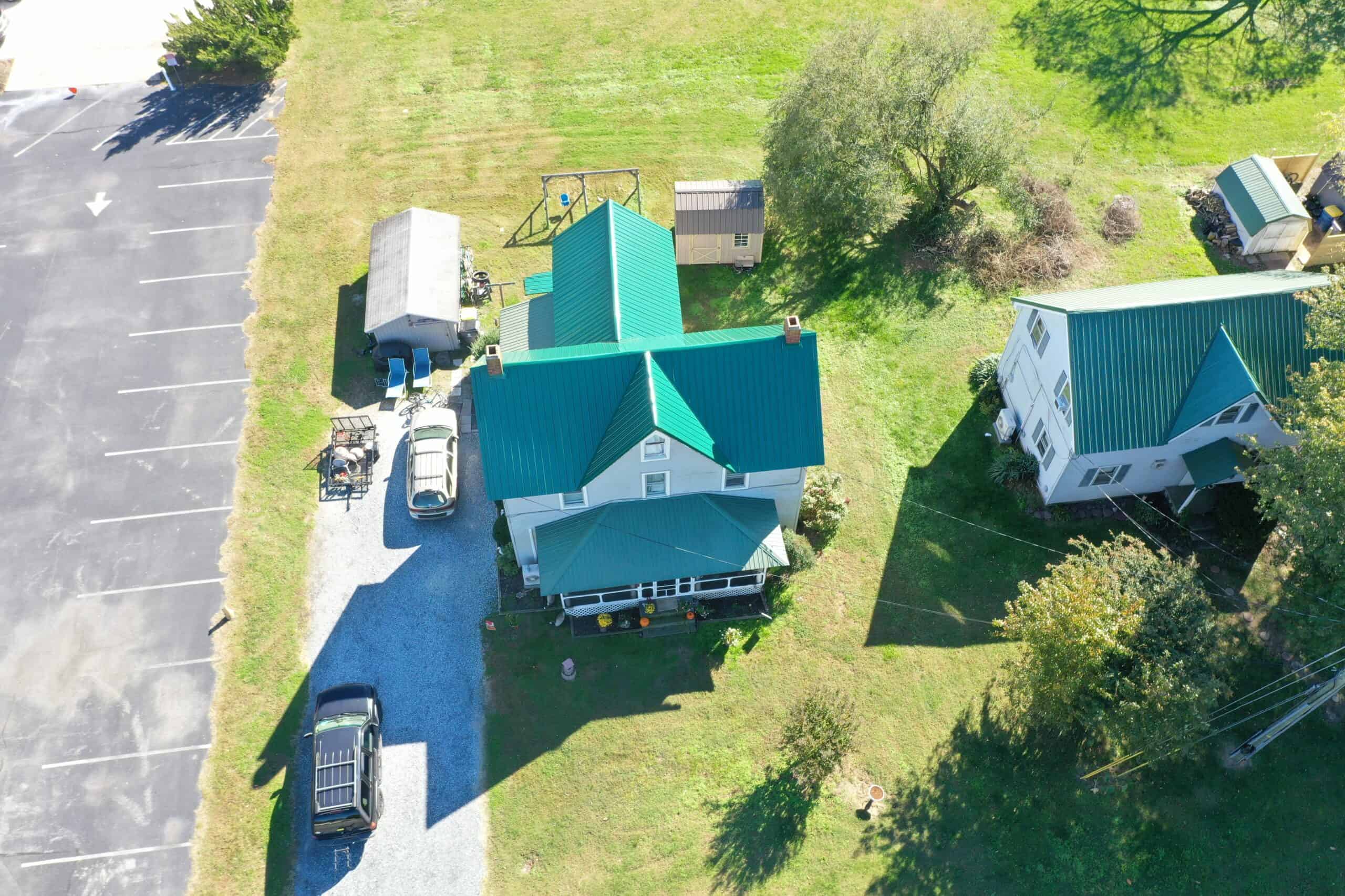 Wide exterior shot of a classic two-story home in Georgetown, DE on a sunny summer day, showing an older asphalt shingle roof with visible wear near the ridge and eaves. Georgetown town streetscape softly visible in background. Real job photo preferred.