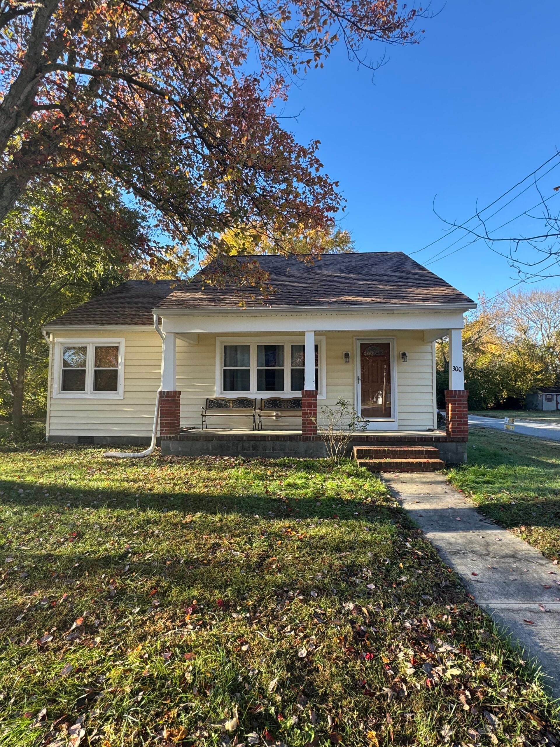 Exterior shot of a single-story home in Hebron, MD on a sunny summer afternoon, showing a full roofline with asphalt shingles in mixed condition. Suburban residential setting with mature trees. Real G and Bros job photo preferred. 