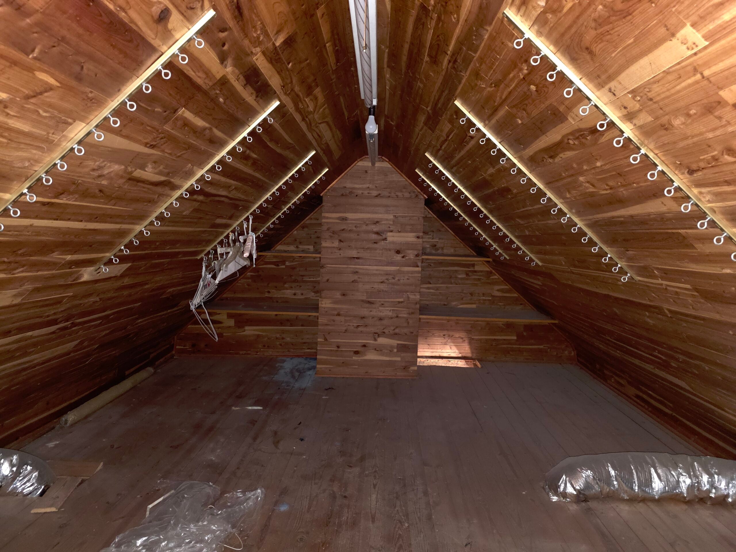 How to Spot a Roof Leak Before Water Hits Your Ceiling 2 | G and Bros Homeowner in an attic with a flashlight inspecting the underside of the roof deck for water stains