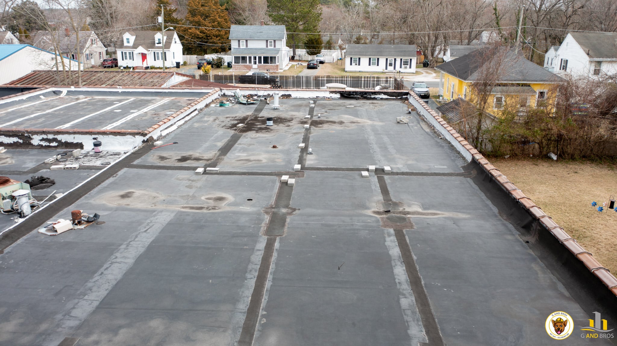 5 Warning Signs Your Commercial Roof Needs Replacement (Not Just Repair) 2 | G and Bros Wide view of an aging commercial flat roof on Delmarva showing ponding areas, worn membrane sections, multiple repairs, and deteriorated flashing