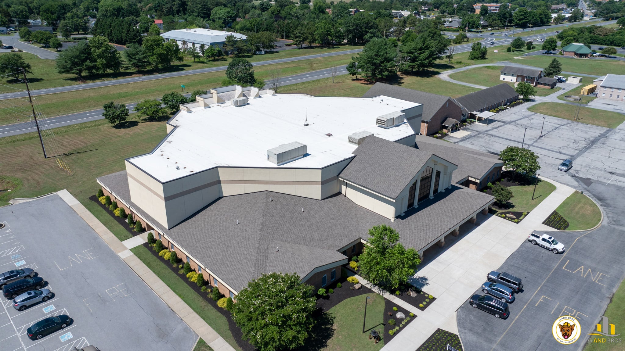 Aerial drone view of the completed roof replacement at Emmanuel Wesleyan Church in Salisbury, Maryland by G and Bros, showing the finished shingle and low-slope roofing systems